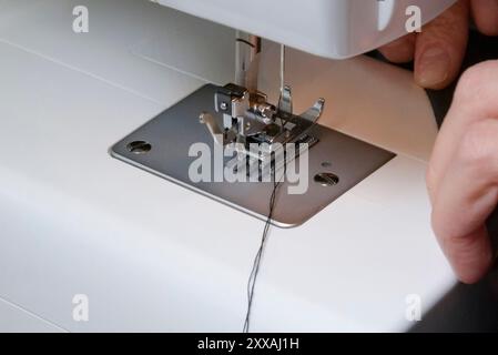 Сorrect position des fils sous l'aiguille. Machine à coudre domestique au travail. Gros plan Banque D'Images