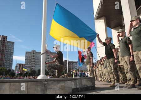 KIEV, UKRAINE - 23 AOÛT 2024 - des soldats hissent le drapeau national devant l'administration d'État du district de Densianskyi le jour du drapeau d'État, Kiev, capitale de l'Ukraine. Banque D'Images