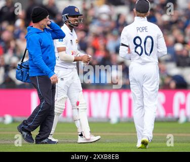 Emirates Old Trafford, Manchester, Royaume-Uni. 23 août 2024. 1er Rothesay Cricket test match, jour trois, Angleterre contre Sri Lanka ; Dinesh Chandimal du Sri Lanka parle avec Ollie Pope, capitaine de l'Angleterre alors qu'il retourne au pavillon après avoir été forcé de se retirer blessé après une blessure à son doigt f crédit : action plus Sports / Alamy Live News Banque D'Images