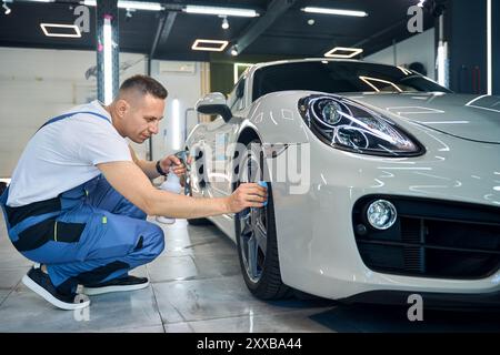 L'employé du service automobile utilise des matériaux spéciaux dans le processus d'esthétique automobile Banque D'Images