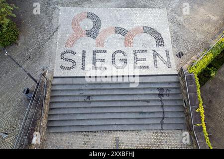 Luftaufnahme. Die Stadt Siegen wird 2024 800 Jahre alt. Zu diesem Anlass wurden am Treppenaufgang zur Nikolaikirche und zum Rathaus Naturpflastersteine mit dem Siegen 800 logo verlegt. Die Pflastersteine wurden vom AWZ Bau Aus- & Weiterbildungszentrum durch sieben Auszubildende verschiedener Firmen verlegt und sind ein Geschenk zum Stadtjubilaeum Stadtjubiläum. Sommer im Siegerland AM 22.08.2024 à Siegen/Deutschland. *** Vue aérienne la ville de Siegen aura 800 ans en 2024 pour marquer l'occasion, des pavés naturels avec le logo Siegen 800 ont été posés à l'escalier du Nikolai CH Banque D'Images