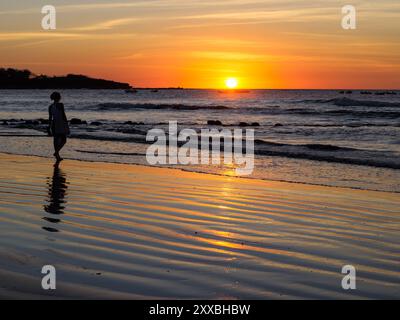 Femme debout sur la plage au coucher du soleil, Tamarindo, Costa Rica Banque D'Images