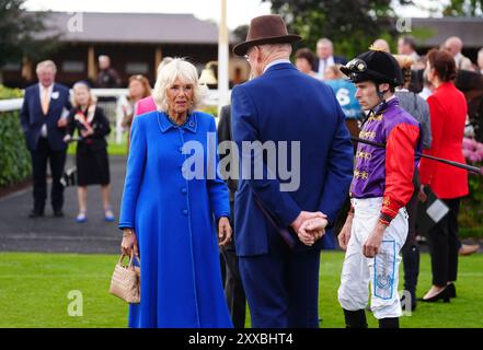 La reine Camilla avec l'entraîneur John Gosden et le jockey Kieran Shoemark pendant la troisième journée du Sky Bet Ebor Festival à l'hippodrome de York. Date de la photo : vendredi 23 août 2024. Banque D'Images