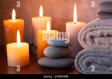 Spa Still Life avec des bougies, serviette et pierres sur une table en bois Banque D'Images
