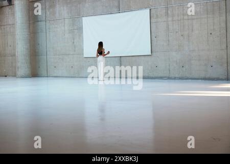 Femme debout dans un grand espace de musée avec des murs blancs. Banque D'Images