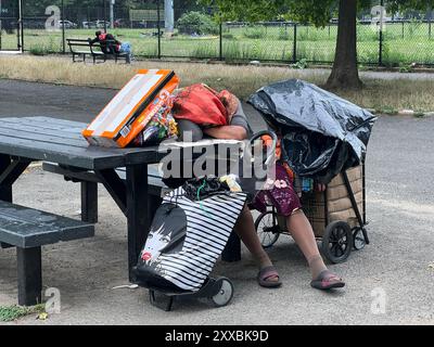 Femme sans-abri fatiguée avec ses affaires dormant à une table à Prospect Park, Brooklyn, New York. Banque D'Images