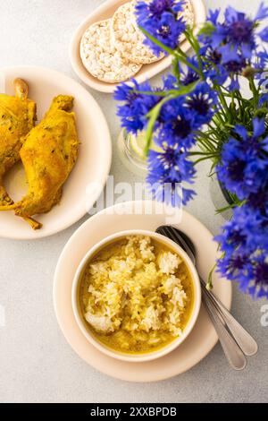 Ragoût de lapin avec du riz, du brocoli et des gâteaux de riz, une table servie avec de la nourriture et un vase de fleurs, un délicieux déjeuner copieux ou dîner Banque D'Images