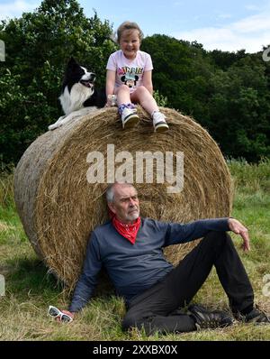 Amusement en famille sur la ferme grand-parent et petit-enfant avec le chien Border Collie sur la balle de foin Shropshire, Angleterre, Grande-Bretagne, Royaume-Uni Banque D'Images