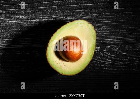 avocat hass tranché sur fond de bois noir vue de dessus Banque D'Images