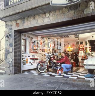 L'homme travaille sur la moto dans le garage équipé de beaucoup de souvenirs rétro Banque D'Images