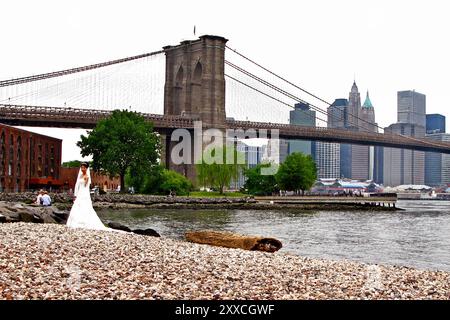 Un couple de jeunes mariés marchant sur la plage de galets dans le Brooklyn Bridge Park dans le quartier DUMBO de Brooklyn Banque D'Images