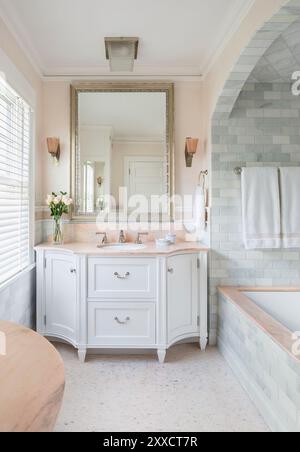 Meuble-lavabo personnalisé dans la salle de bains avec accents roses à côté de la douche cintrée Banque D'Images