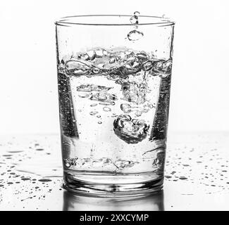 Eau versée dans un verre. Arrière-plan blanc Banque D'Images