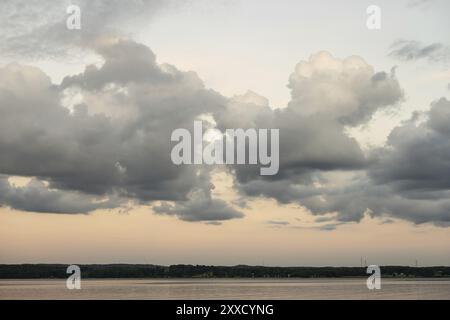 Des nuages puissants au-dessus d'un lac avec des éoliennes à l'horizon Banque D'Images