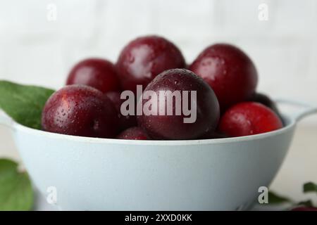 Prunes mûres dans une passoire sur la table, gros plan Banque D'Images