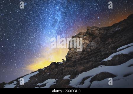 Décor de nuit réalisé sur une longue exposition. Un beau paysage caucasien de roches rouges sur fond de la voie lactée froide et un re jaunâtre chaud Banque D'Images