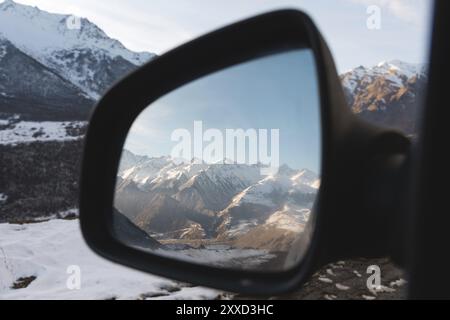 Reflet d'un beau paysage de montagne au coucher du soleil dans le miroir latéral de la vue arrière. Le concept de voyager en voiture. Montagnes du Caucase à UPP Banque D'Images