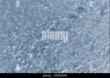 Gros plan de la surface d'un fragment d'un glacier avec une structure de rayures et de bulles. Texture bleu glace à la lumière. Petit DOF Banque D'Images