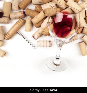 Une photo au-dessus d'un verre de vin rouge avec des bouchons et un tire-bouchon, prise du haut sur un fond blanc. Une invitation à une dégustation de vin, design templa Banque D'Images