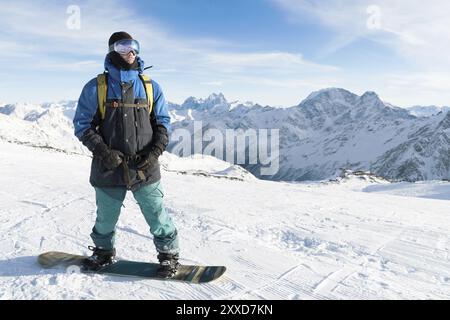 Un snowboarder professionnel se tient debout avec son snowboard sur fond du volcan Elbrus endormi. Caucase du Nord. Approvisionnement publicitaire Banque D'Images