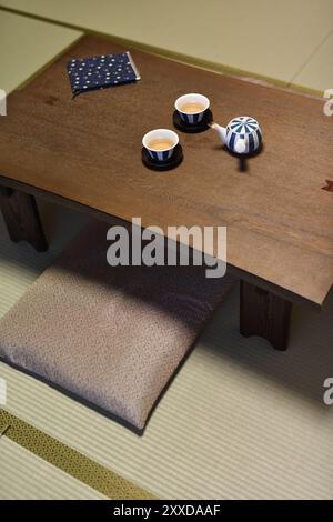 De courtes pattes japonais table à thé en bois, Chabudai, avec une théière et deux tasses, coussins zabuton, assis sur les tatami, d'une chambre traditionnelle japonaise Banque D'Images