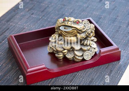 La grenouille monétaire feng shui symbole de prospérité avec la pièce sur la table en bois encore-vie Banque D'Images