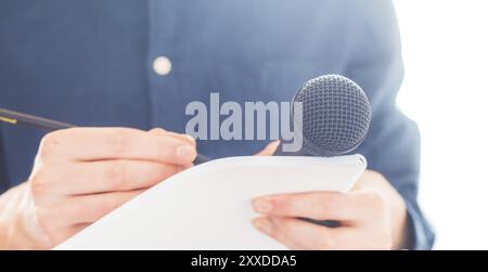 Cut-out d'un journaliste mâle dans un maillot bleu lors d'une conférence de presse qui est la prise de notes et la tenue d'un microphone Banque D'Images