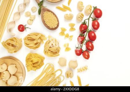 Une photo prise à la verticale de différents types de pâtes, y compris spaghetti, penne, fusilli, et d'autres, avec des tomates cerises, tourné à partir de ci-dessus, sur un white backg Banque D'Images