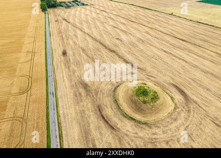 Une route passe devant un ancien monticule funéraire dans la campagne de Skamby sur l'île de Funen, au Danemark Banque D'Images