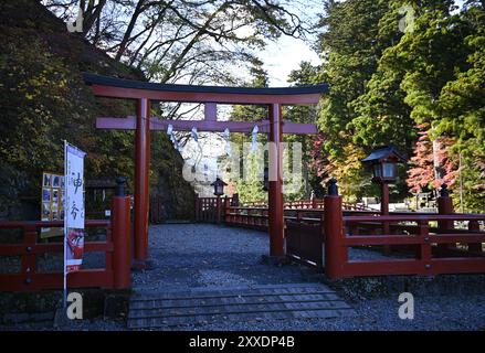 Vue panoramique d'une ancienne porte Shinto Torii en bois laqué vermillon à l'entrée du pont Shinkyō, traversée d'une rivière sacrée à Nikkō, Japon. Banque D'Images