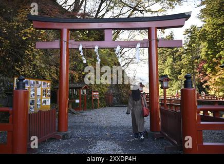 Vue panoramique d'une ancienne porte Shinto Torii en bois laqué vermillon à l'entrée du pont Shinkyō, traversée d'une rivière sacrée à Nikkō, Japon. Banque D'Images