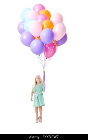 Petite fille, volant et flottant avec des ballons colorés dans l'air pour l'hélium, anniversaire ou événement en studio sur un fond blanc. Jeune femme Banque D'Images