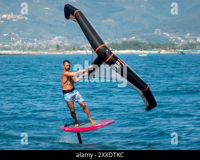 Fiumaretta di Ameglia, Italie - 22 août 2024 : L'homme pratique le fleuret dans la mer ligure. Wing foil est un sport nautique dynamique combinant le surf et le K. Banque D'Images