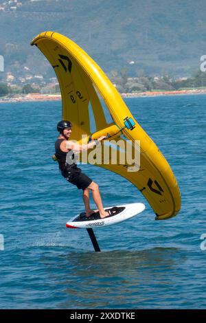 Fiumaretta di Ameglia, Italie - 22 août 2024 : L'homme pratique le fleuret dans la mer ligure. Wing foil est un sport nautique dynamique combinant le surf et le K. Banque D'Images