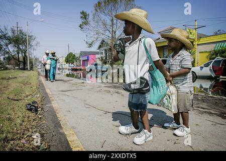 Tyreen et Tyreese Phyllis attendent que leur mère Cheryl guide leur grand-père aveugle Lewis sur la terre ferme. Cinq jours après que l'ouragan Katrina eut touché terre à la Nouvelle-Orléans, la famille s'est finalement sortie à l'abri de leur quartier inondé dans le district de Lower Ninth Ward. Alimenté par une eau exceptionnellement chaude dans le golfe du Mexique, l'ouragan Katrina a été le plus coûteux de l'histoire des États-Unis et a causé au moins 1833 morts. Les phénomènes météorologiques extrêmes augmentent en fréquence en raison du réchauffement de la planète. Banque D'Images