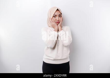 Portrait d'une mignonne femme musulmane asiatique portant un foulard, et se sentant excitée et isolée par un fond blanc. Banque D'Images