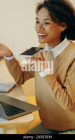Une jeune femme est engagée dans une conversation virtuelle tout en étant confortablement assise à la maison Banque D'Images