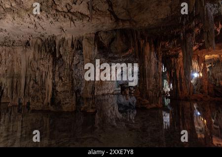 Grande grotte avec de grandes colonnes et leur reflet dans l'eau au fond de la grotte de Neptune en Sardaigne, Italie, avec éclairage artificiel et Banque D'Images