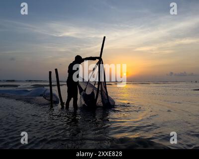 Industrie de la pêche au Bangladesh. Les pêcheurs jettent des filets dans le bazar de cox pendant le coucher du soleil. Contexte économique du Bangladesh. Pêcheur bangladais au coucher du soleil Banque D'Images