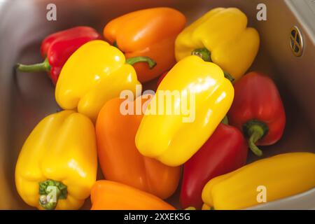 Poivrons jaune vif, orange et rouge dans un évier métallique Banque D'Images
