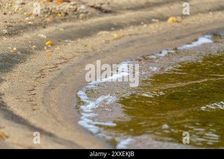 Une vue rapprochée de l'eau claire ondulant doucement sur des galets colorés au fond d'un lac, mettant en évidence les textures naturelles et la transparence de th Banque D'Images
