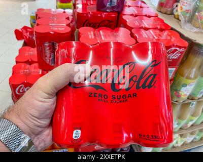 Allemagne Berlin 23 août 2024. Une personne tient une canette de Coca-Cola Zero Sugar. Un magasin avec de nombreux produits Coca-Cola exposés Banque D'Images