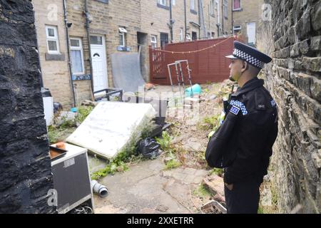 La police devant l'arrière d'une maison dans Minnie Street, alors que la police du West Yorkshire a déclaré qu'un certain nombre de mandats avaient été exécutés dans la zone Keighley de Bradford pendant la nuit en relation avec l'incendie mortel du 21 août. Deux autres personnes ont été arrêtées sur suspicion de meurtre suite à l'incendie de la maison qui a tué une mère et trois enfants à Bradford. Date de la photo : samedi 24 août 2024. Banque D'Images