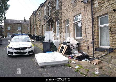 La police devant une maison dans Minnie Street, alors que la police du West Yorkshire a déclaré qu'un certain nombre de mandats avaient été exécutés dans la zone Keighley de Bradford pendant la nuit en relation avec l'incendie mortel du 21 août. Deux autres personnes ont été arrêtées sur suspicion de meurtre suite à l'incendie de la maison qui a tué une mère et trois enfants à Bradford. Date de la photo : samedi 24 août 2024. Banque D'Images