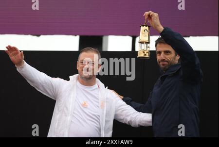 Stoke Mandeville, Grande-Bretagne. 24 août 2024. Tony Estanguet (à droite), président du comité organisateur des Jeux Olympiques et Paralympiques de Paris 2024, tient la lanterne pendant la cérémonie d'allumage de la torche paralympique des Jeux Paralympiques de Paris 2024 à Stoke Mandeville, Grande-Bretagne, le 24 août 2024. Crédit : Li Ying/Xinhua/Alamy Live News Banque D'Images