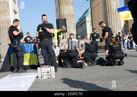 Berlin, Allemagne, 24 août 2024. Cette image montre des officiers de police berlinois qui arrêtent un homme lors d'un événement du jour de l'indépendance ukrainienne près de la porte de Brandebourg. L'individu, qui portait un couteau, s'était blessé avant d'être soumis aux forces de l'ordre. Des agents sont vus en train de sécuriser le suspect sur le terrain et de préparer une aide médicale à côté d'un véhicule de police, tandis que des spectateurs et du matériel de l'événement sont visibles en arrière-plan de l'opération de sécurité dans la capitale. Felix Wolf/Alamy Live News Banque D'Images