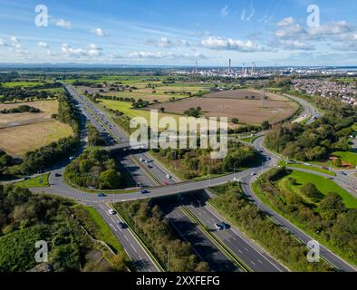 Trafic sur l'autoroute M56 à la jonction 14, Helsby avec la raffinerie de pétrole Stanlow en arrière-plan, Cheshire, Angleterre Banque D'Images