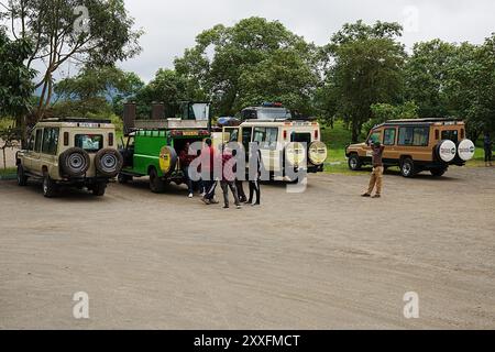 ARUSHA, TANZANIE - 19 juillet 2024 : véhicules tout-terrain en stationnement dans le parc national africain, ciel nuageux dans la chaude journée d'hiver. Banque D'Images