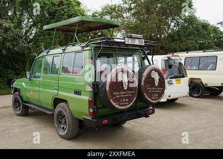 ARUSHA, TANZANIE - 19 juillet 2024 : véhicule tout-terrain vert sur parking dans le parc national africain, ciel nuageux dans la chaude journée d'hiver. Banque D'Images