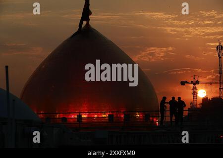 Karbala, Irak. 24 août 2024. Le soleil se couche derrière le sanctuaire de l'Imam Hussein alors que les musulmans chiites prennent part aux rituels de deuil à Karbala pour les commémorations Arba'een qui marquent la fin de la période de deuil de 40 jours pour le meurtre du petit-fils du prophète Mohammad, l'Imam Hussein, au VIIe siècle. Crédit : Ameer Al-Mohamedawi/dpa/Alamy Live News Banque D'Images